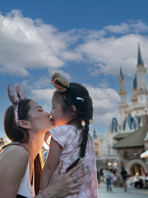 Asian mother kissing adorable kid daughter, travel at the theme